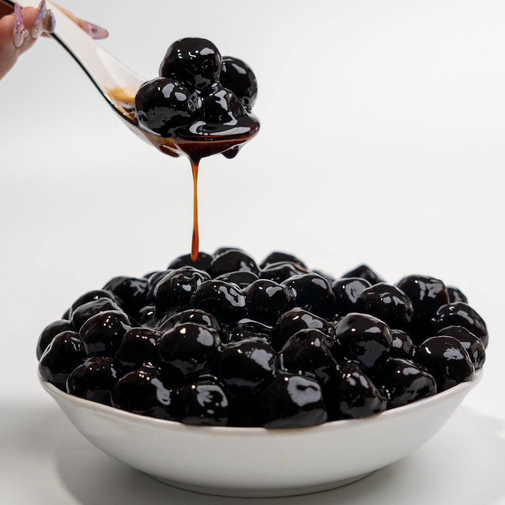 15 Topping Ăn Với Tàu Hũ Ngon: Từ Truyền Thống Đến Menu Kinh Doanh 5 Bát trân châu đen bóng bẩy ngập sốt đường đen và muỗng múc từng viên trân châu dẻo dai