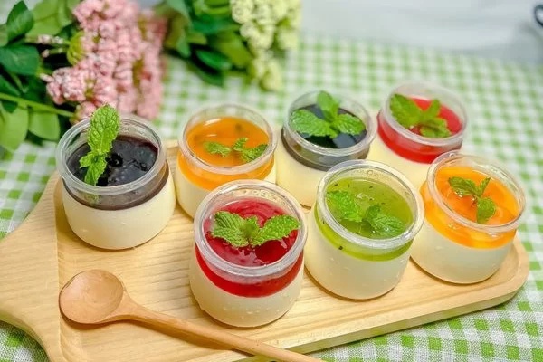 Panna cotta để được bao lâu trong tủ lạnh? Cách bảo quản đúng 5 Khay gỗ đựng các hũ thủy tinh panna cotta phân tầng với nhiều vị sốt trái cây dâu việt quất chanh leo và lá bạc hà