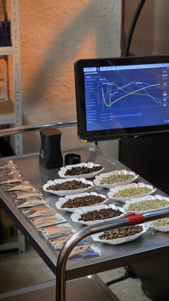 Cách Tính Cost Cà Phê Sữa, Latte Và Các Món Cà Phê Trong Menu 4 Màn hình kỹ thuật số hiển thị biểu đồ rang hạt cà phê cạnh khay nếm mẫu hạt xanh và hạt rang cupping